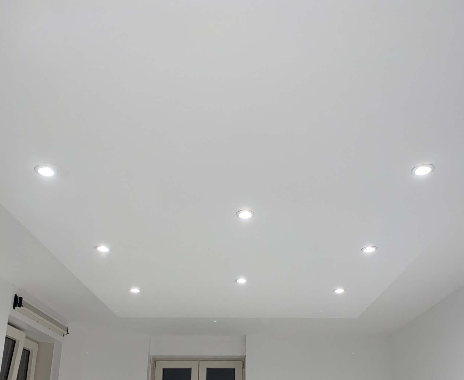 Acht inbouwspots in een wit plafond boven openslaande deuren